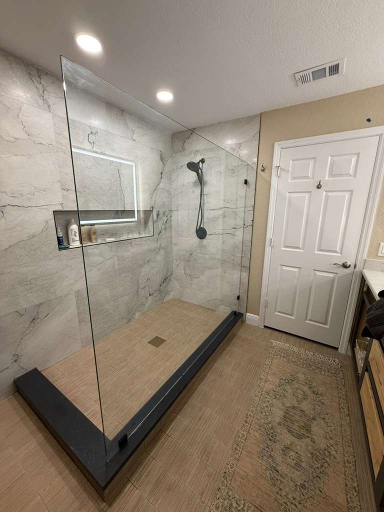Remodeled shower with glass enclosure and gold hardware
