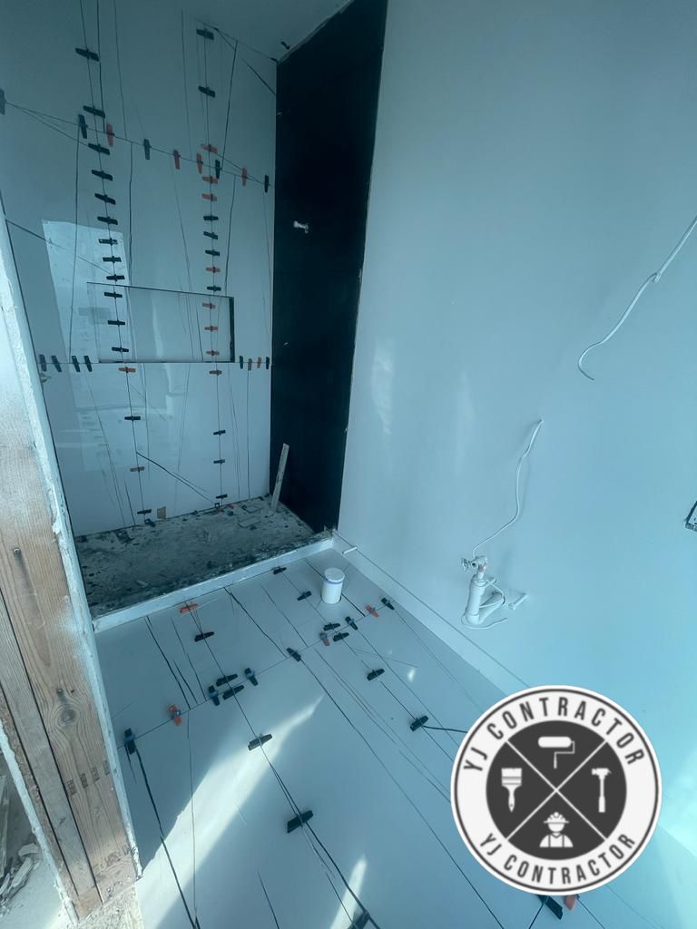 Bathroom floor and shower tile installation in progress with leveling clips