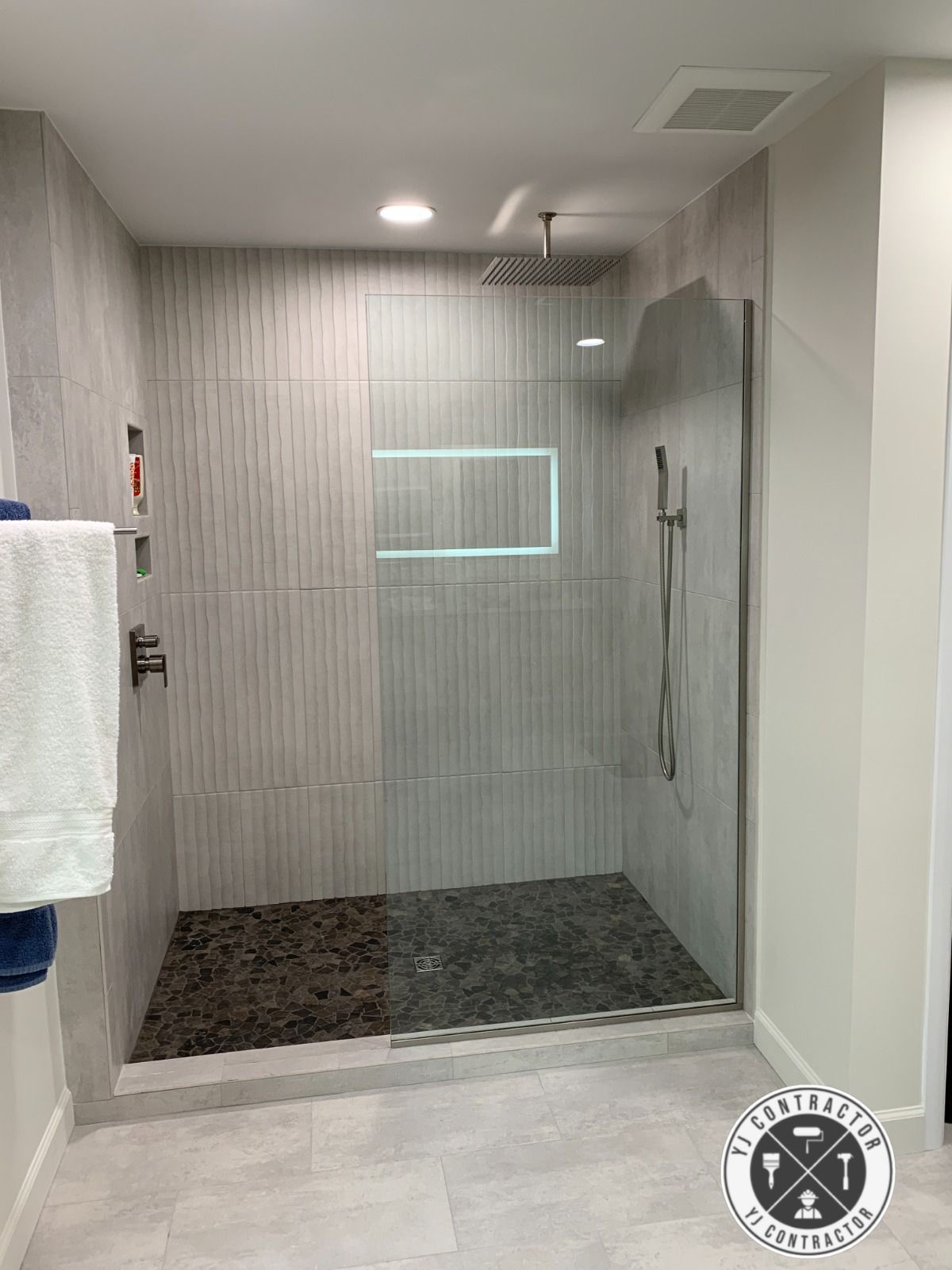 Completed walk-in shower with glass panel, rain head and tiled walls