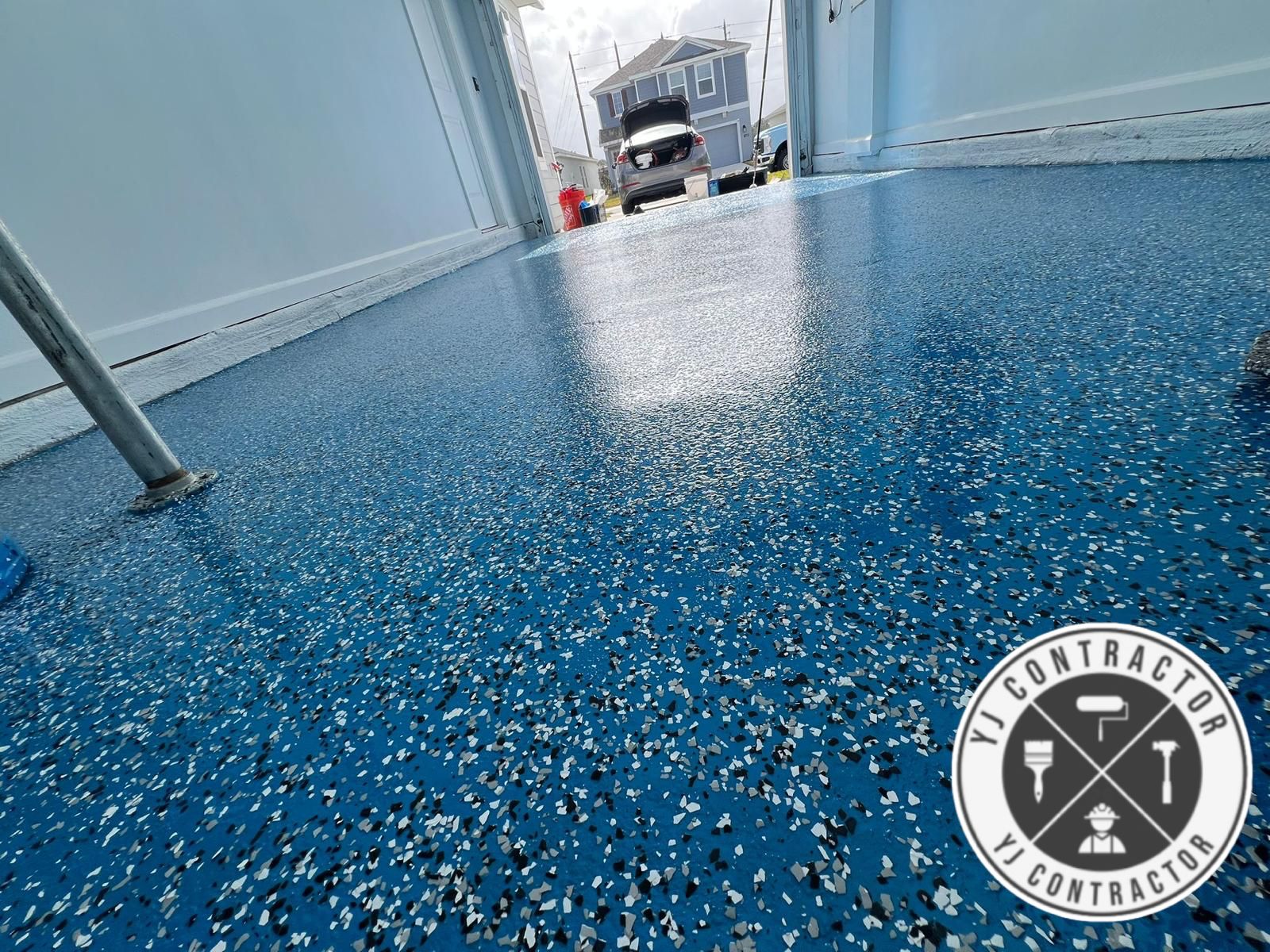 Close view of blue and gray flake epoxy flooring at a garage doorway