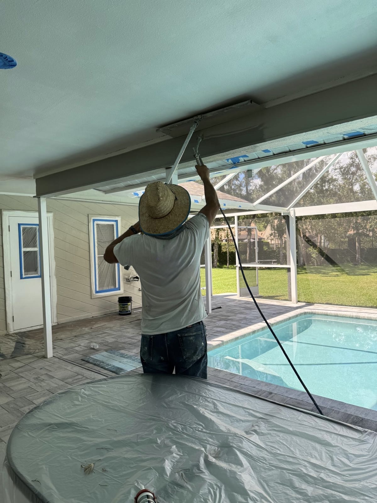 Painter applying paint to a covered pool patio